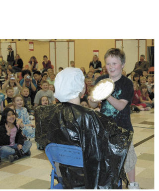 Elk Ridge Elementary School student Kai  McKorkle is all smiles as he prepares to hit Principal Christi Ellenwood with a pie during a recent assembly. His deed was a school reward for raising plenty of food for the Buckley Food Bank during January. Also part of the fun was teacher Michelle Simonson’s portrayal of a chick and her rendition of the chicken dance for  students. For a complete story