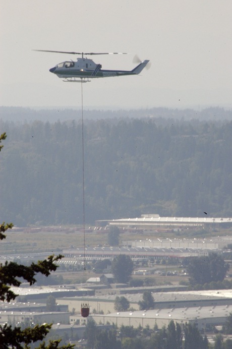 A helicopter drops water on a brush fire at Eli Hill along state Route 410 in Bonney Lake