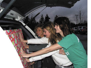 Rachel and Malia Mason and Jaclyn Akers load an appliance-sized box full of donated toys into Mason’s van Dec. 12 at Deiringer Heights Elementary School in Lake Tapps.