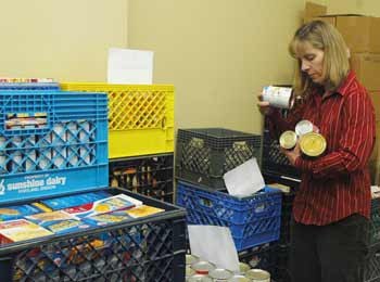 Plateau Outreach Ministries Executive Director Britt Nelson gathers canned goods from the food bank's dwindling stocks.