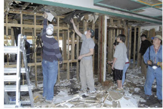 Volunteers from the Church of Jesus Christ of Latter Day Saints of Sumner pull down ceiling tile to help the congregation of the First Pentecostal Church renovate a building formerly owned by St. Andrews Catholic Church.