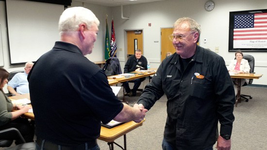 Victor Proulx shakes Fire Commissioner Dave Mitchell's hand after Proulx is sworn in as a new commissioner.