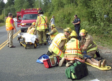 East Pierce Fire and Rescue emergency personnel assist two victims of a one-vehicle rollover accident Saturday