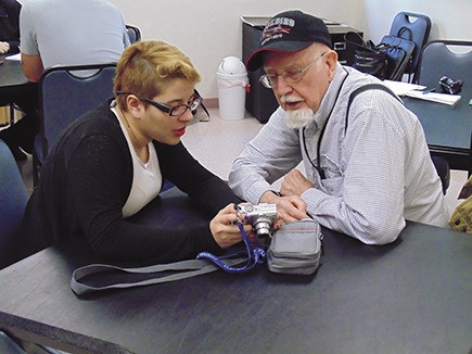 Puyallup resident Lee Brown looks on as Sumner High School senior Katherine Marroquin shows him features on his digital camera during a free Technology Days class at the Sumner Senior Center Jan. 22.