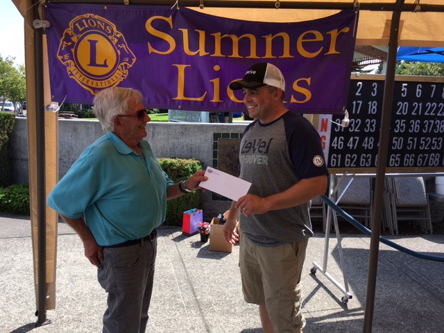 Sumner Lions Club President Emerson Bishop presents Mike Cross with his raffle winnings during the 2016 Sumner's Rhubarb Days.
