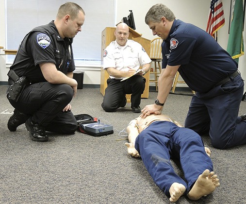 Bonney Lake Police Officer Todd Green simulates officer AED training with East Pierce Battalion Chief Jeff Moore and Lieutenant Brad Dyson.