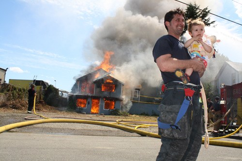 An East Pierce firefighter and his daughter mug for a family photograph in front of 642 West Main Street