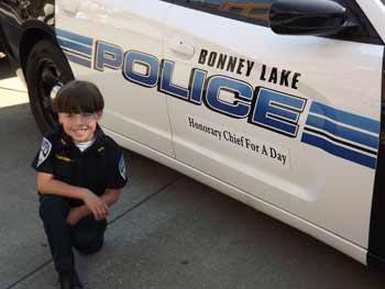 Chief For a Day William Knight III poses in front of the car that carried him to the Aug. 16 event at CenturyLink Field and the Criminal Justice Training Center in Burien.