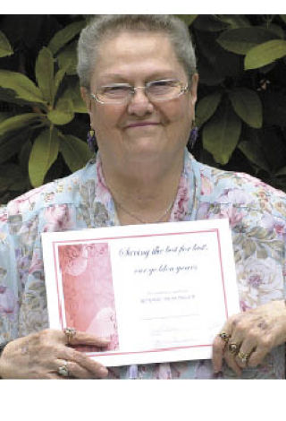 Bonnie Messinger holds up her certificate for winning first place in the essay contest.