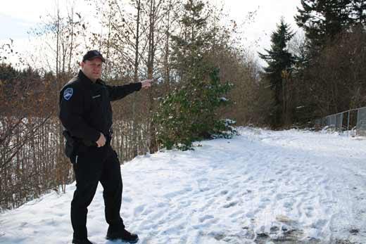 School Resource officer Daron Wolschleger points to a hole in the fence surrounding Bonney Lake High School near where a trail through the greenbelt behind the schools meets 198nd Street in Bonney Lake.
