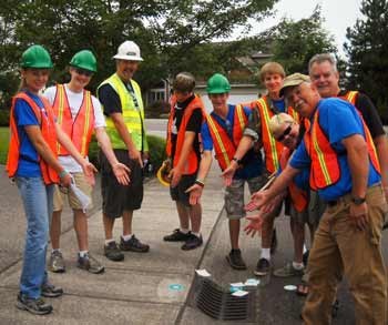 Cameron Gehrke and his crew pose for a photo while placing warning labels on drains in Bonney Lake.