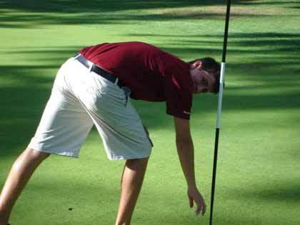 Jake Erickson plucks his hole-in-one ball from the cup.