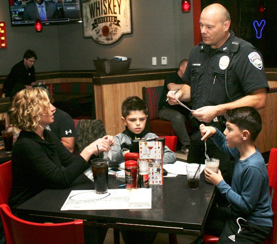 Officer Daron Wolschleger explains Tip-A-Cop to a family eating at Red Robin on Oct. 24.