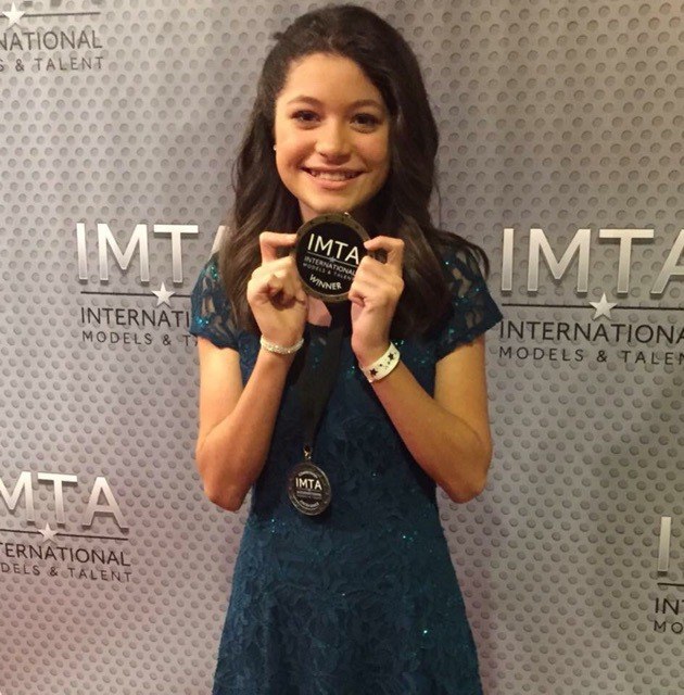Saveya Boyle holds her two IMTA medals on the red carpet in Los Angeles.