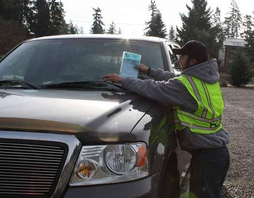 Bonney Lake Police Department intern Scott Williams places on a car windshield a warning about car prowls.