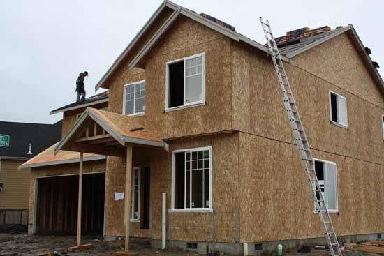 A worker lays shingles on a house under construction in the Panorama West neighborhood of Bonney Lake.