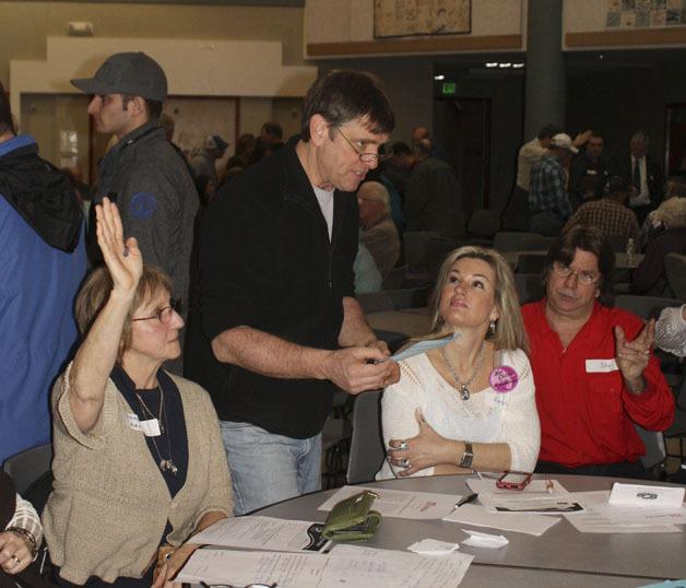 Steve Garman asks the group questions during the Pierce County 31st District Republican caucus at  North Tapps Middle School Saturday. Raising her hand on the left is Kathy May