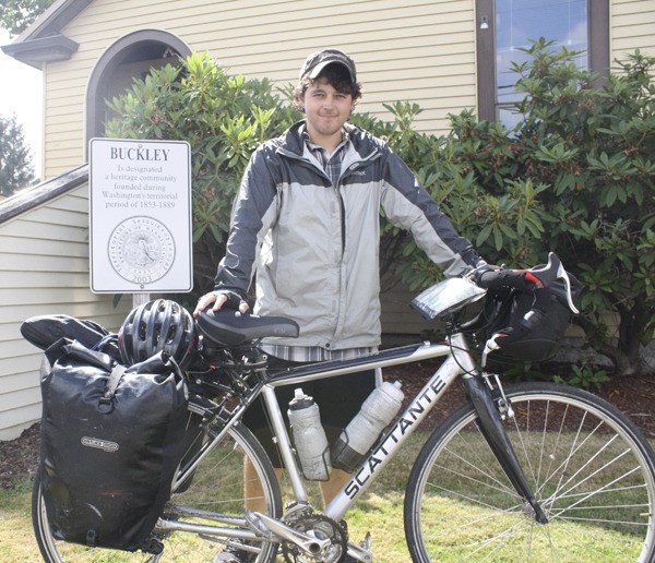 Ryan Buckley stands in front of Buckley City Hall with the bicycle he rode from Virginia Beach.