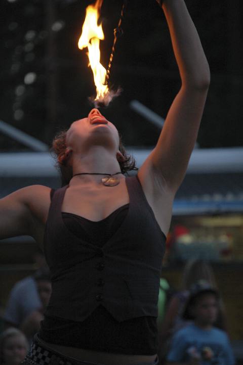 A fire dancer puts her lips to the flame during a showcase at Bonney Lake Days