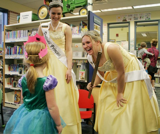 Princess Tabitha (right) from Bonney Lake High School and Princess Maddie (left) from White River High School tap and crown Kylie as a princess in training at the Buckley library on Feb. 6.