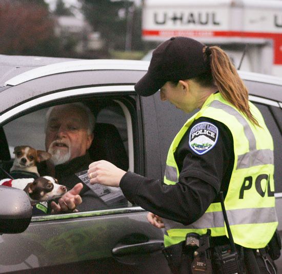Bonney Lake officer Tobie Johnston hands out a flyer to a resident during Friday’s Holiday Park Smart Program.
