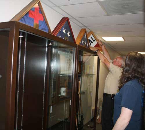 Assistant Chief John McDonald arranges flags atop a new display case memorializing former chief Dan Packer
