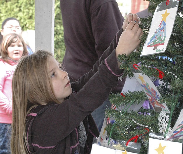 Angel Johnston adds her creation to the tree.