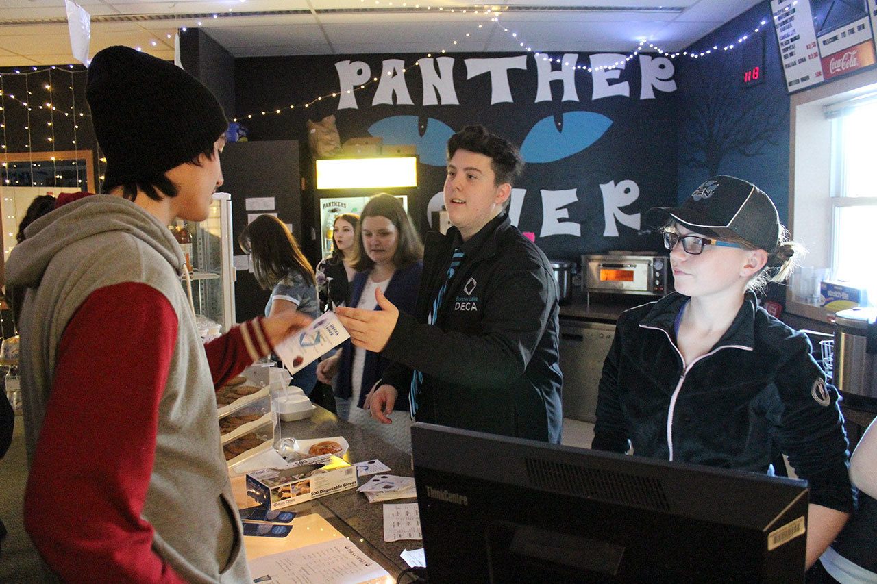 Bonney Lake High School DECA President David Azure hand students stickers and flyers advertising their Death by Chocolate event on April 8, 2017. Photo by Ray Still.