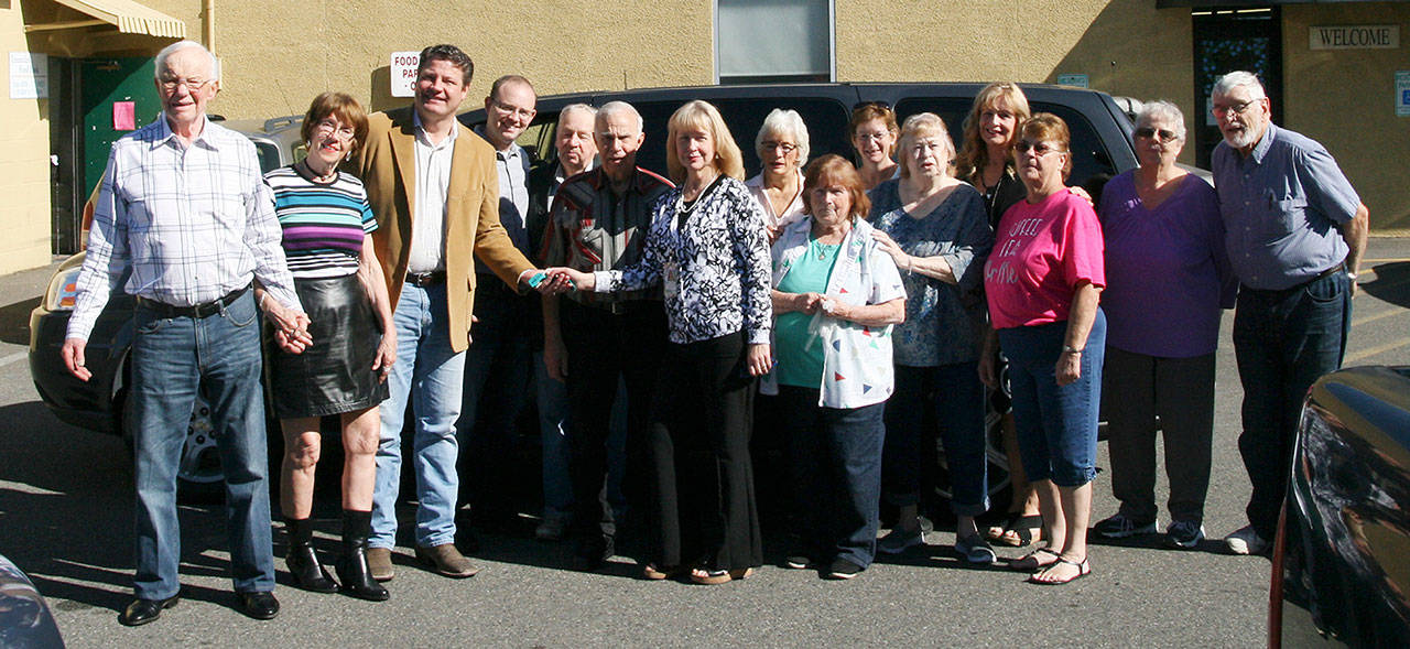 Enumclaw Senior Center manager Jobyna Nickum shakes hands with King County Councilman Reagan Dunn after he donates a surplus carpool van to the center. Submitted photo.