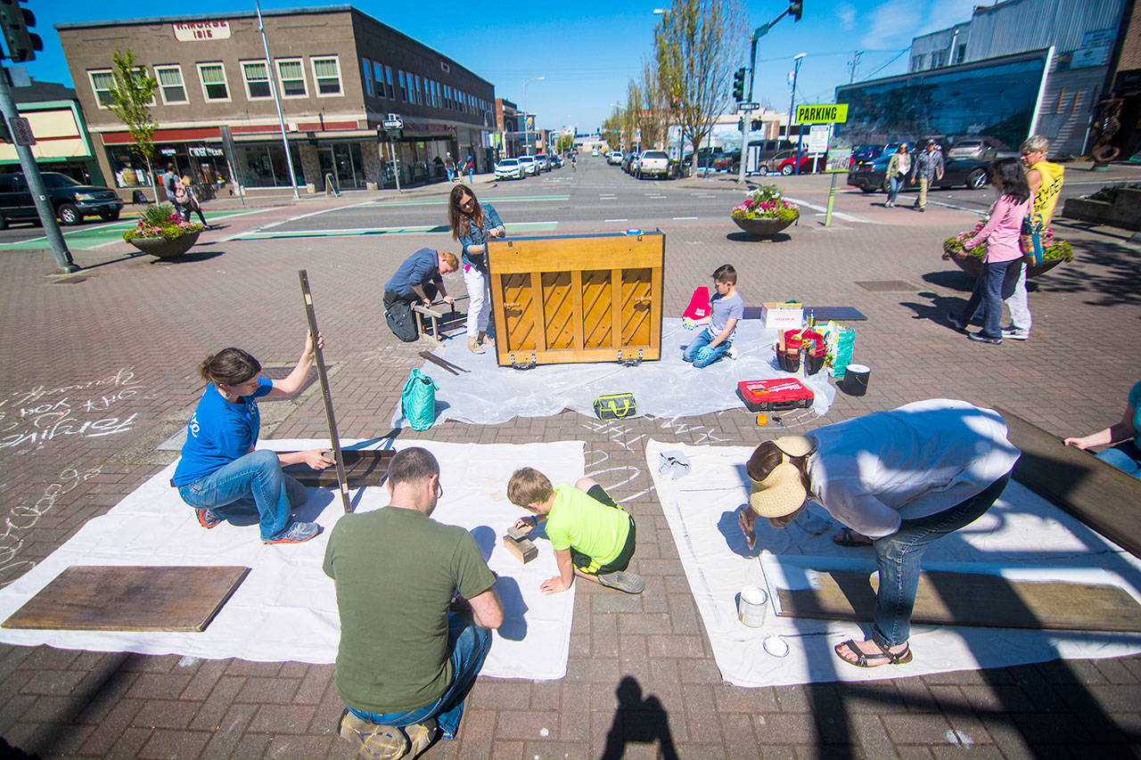 A work party on Saturday prepares Port Angeles downtown piano for a makeover on Saturday. (Jesse Major/Peninsula Daily News)