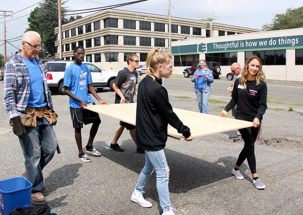 Carrying Enumclaw’s Youth Center’s new backdoor is Scott Karanja and Christian Sprague in the back, and Olivia Robbins and Ava Jenkins in the front. In the background, Sue Z. Hart takes photos. PHOTO BY RAY MILLER-STILL
