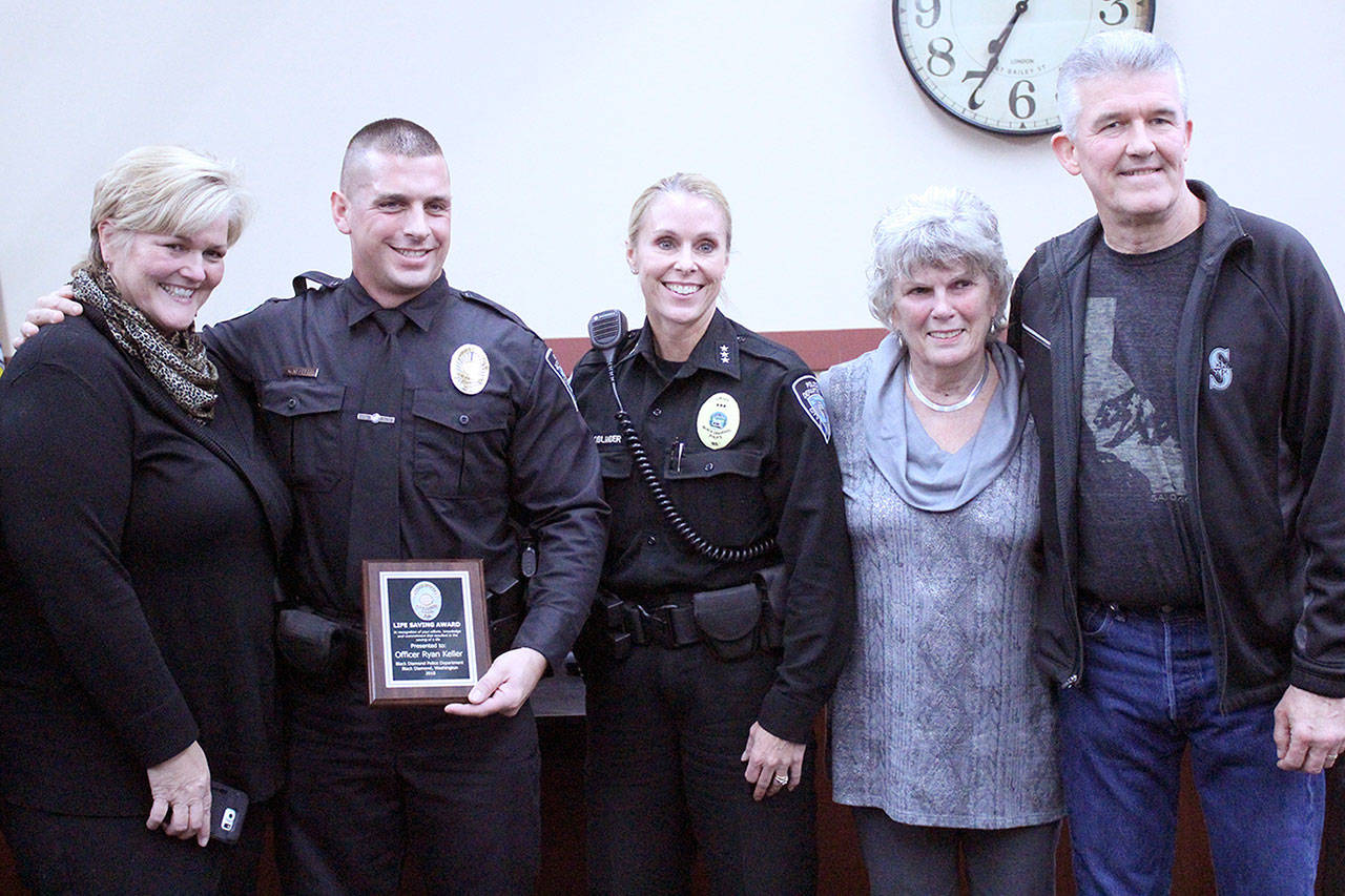 From left to right, Teri Moore, Officer Ryan Keller, Police Chief Jamey Kiblinger, Mayor Carol Benson, and Joe Moore after Keller was given the Life Saving Award. Photo by Ray Still