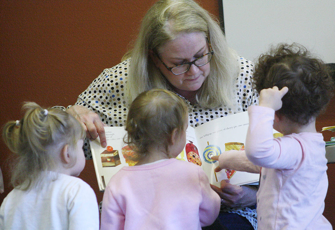 Catherine OBrien, youth services librarian, keeps kids attention during an Oct. 11 session of Family Story Time at the Bonney Lake library. The hour-long program also included games and interactive play with a colorful parachute. KEVIN HANSON PHOTOS