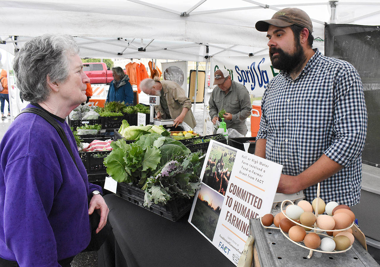 Kevin Halfrick greets a customer during last weeks debut of the Enumclaw Plateau Farmers Market. He will staff the Hell or High Water Farm tent each week. Photo by Kevin Hanson