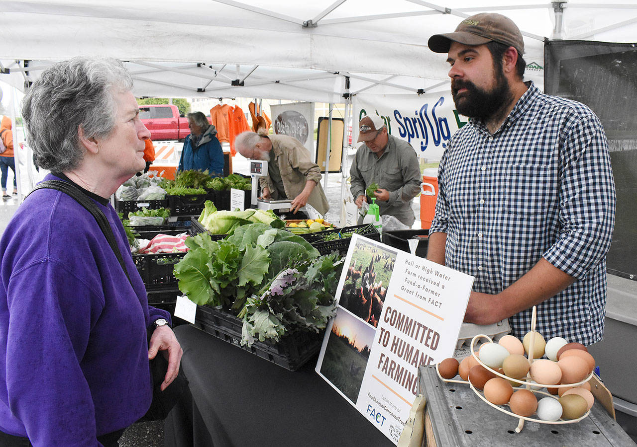 Kevin Halfrick greets a customer during last week’s debut of the Enumclaw Plateau Farmers Market. He will staff the Hell or High Water Farm tent each week. Photo by Kevin Hanson