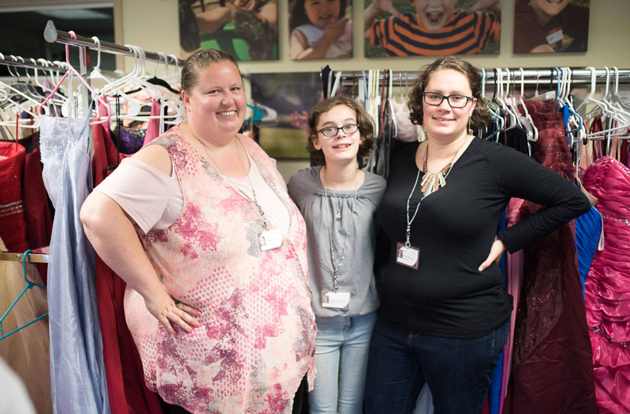 Amanda Lawson, left, and Nicole McCoy, right, along with Nicole’s daughter, Jillian — who volunteers on a regular basis — in the middle at their storage and fitting space in Orting. Photo by Crystal Kennedy/Special Portraits