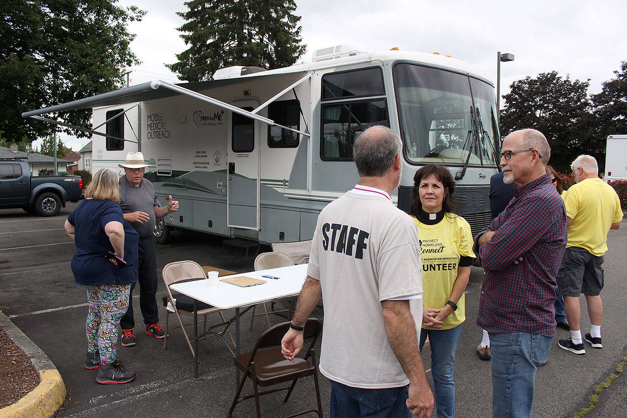 Dale Clark, second to the far left, is speaking with another volunteer during a June 14 Project Homeless Connect event during at Puyallup’s Nazarene Church. Dale himself is no stranger to how expensive the U.S.’s healthcare system is, since he has survived cancer three times, and his wife has other severe medical issues. Photo by Ray Miller-Still