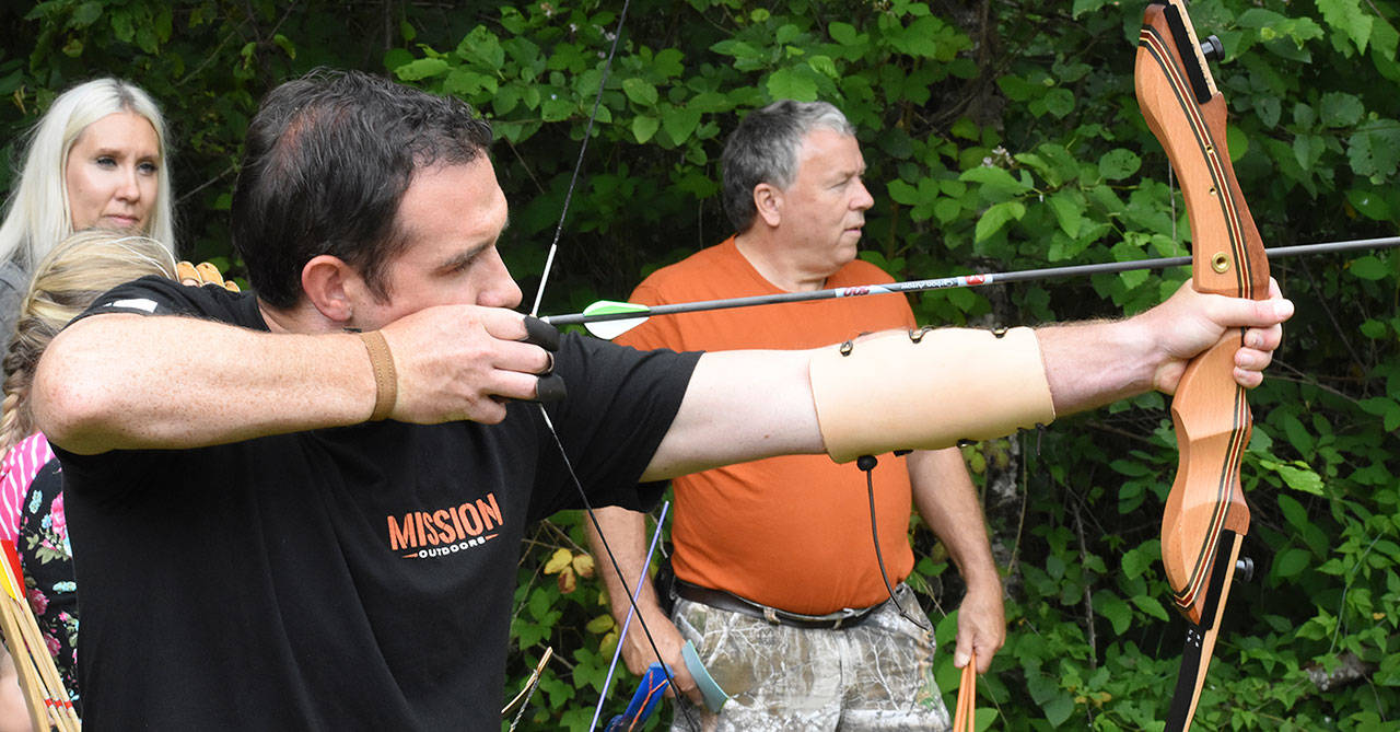 A Mission Outdoors participant takes aim Saturday. Looking on are Butch Loney from Flint Tip Archers and Shannan Hansen with Mission Outdoors. Photo by Kevin Hanson