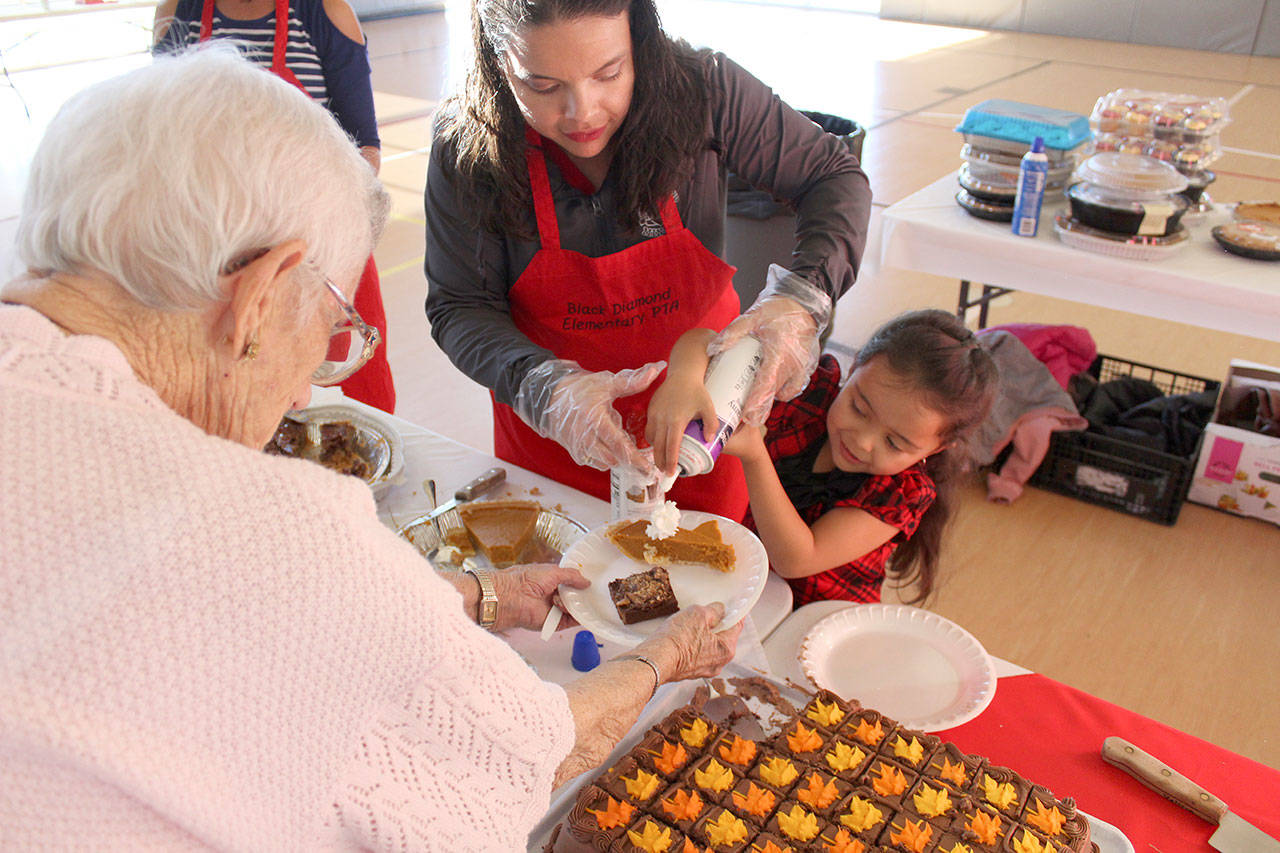 Emily Castro Serrato, 6, helps serve dessert to Marceil Quaale, who was celebrating her 88th birthday at the event. Photo by Ray Miller-Still