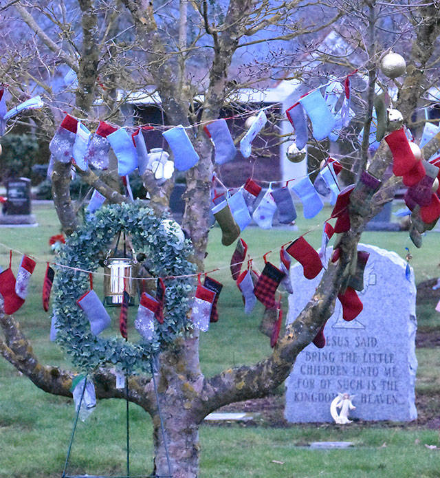Many people were touched by the kindness of someone who placed small Christmas stockings on a tree in the infant section of Enumclaw Evergreen Memorial Park. Each was adorned with the name of a baby buried at the cemetery. The act was done anonymously and, according to cemetery staff, meant a lot to the many families who have children buried there. Photo by Kevin Hanson