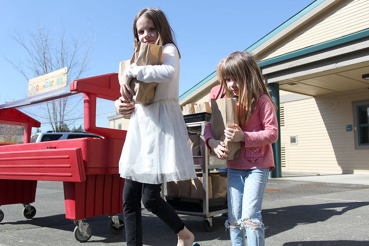 The White River and Enumclaw school districts are expanding their summer food programs for students — more people are able to receive free food at more places around the Plateau. Pictured are Evelyn and Emma Andreasen picking up a lunch at Mountain Meadow Elementary in Buckley when the schools first started their COVID food program. File photo by Ray Miller-Still