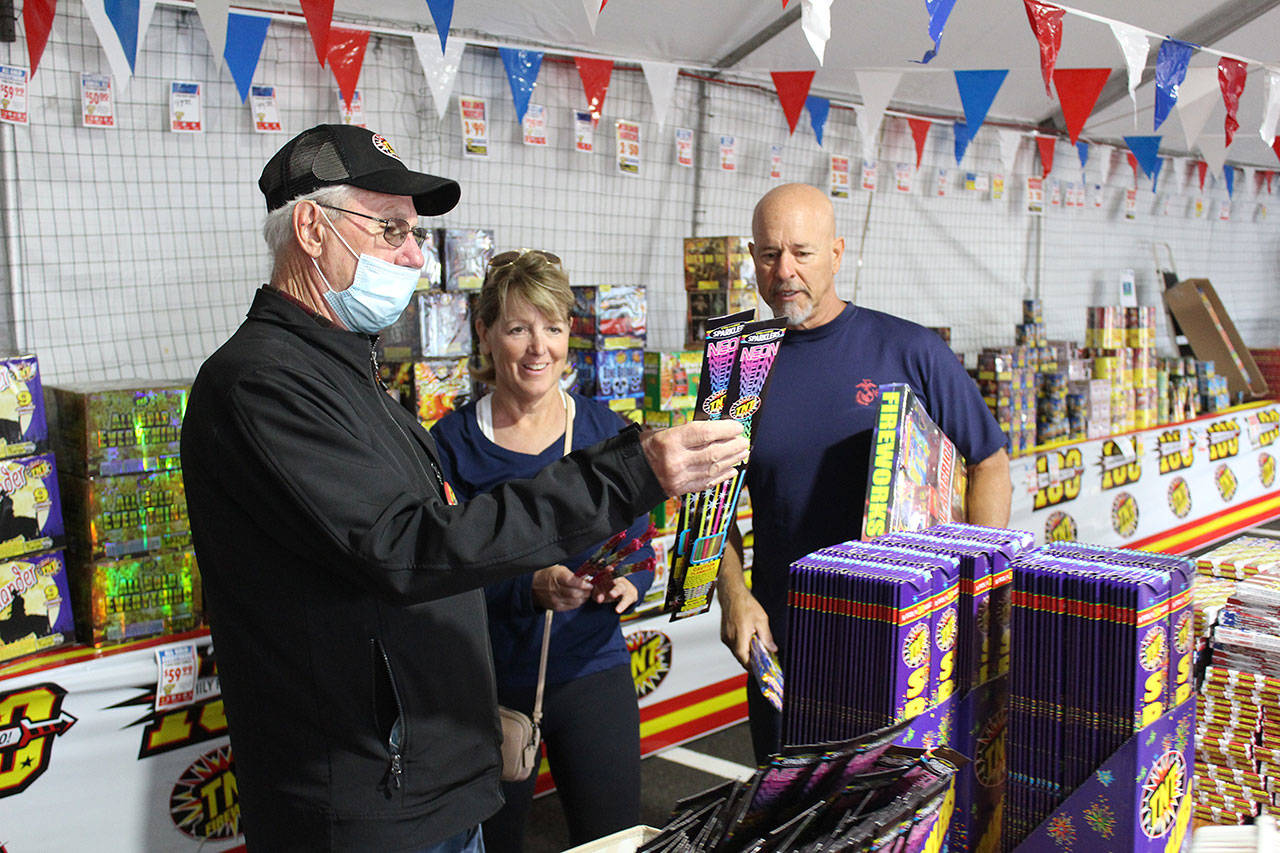 Pastor Jim Dunn shows a couple some safe fireworks for their little ones this upcoming Independence Day. Sponsored by the local St. Baptist Church, this TNT Firework stand has been here 15 years, and all proceeds go toward church sports programs. Photo by Ray Miller-Still