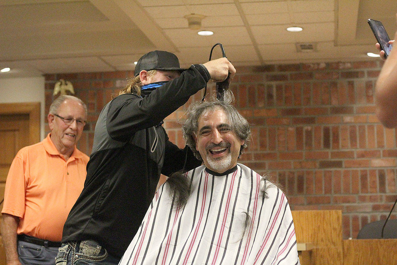 Enumclaw Mayor Jan Molinaro was shaved by local barber and former City Councilman Chuck Anselmo, who oversaw four Enumclaw High School graduates and wrestlers — Drew Krehbiel, Brandon Cromier, Aiden Carroll (pictured), and Cole Bower — as they made first contact with the mayor’s shaggy mane. Photo by Ray Miller-Still