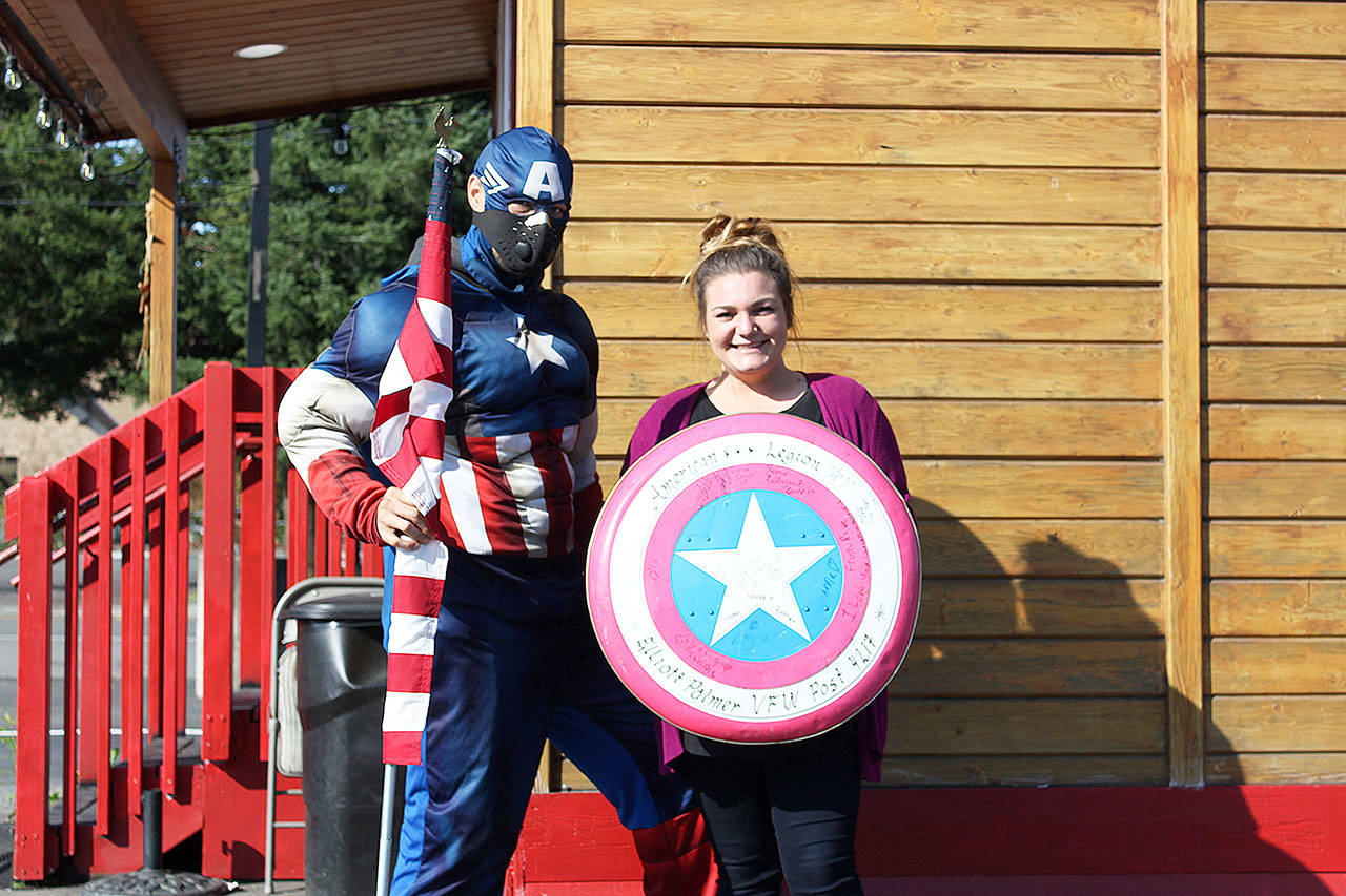 Allen Mullins, a.k.a. Captain America, stands outside the Blazing Glory coffee house off SR 410 with barista Roslyn before he took off to Yakima. Photo by Ray Miller-Still