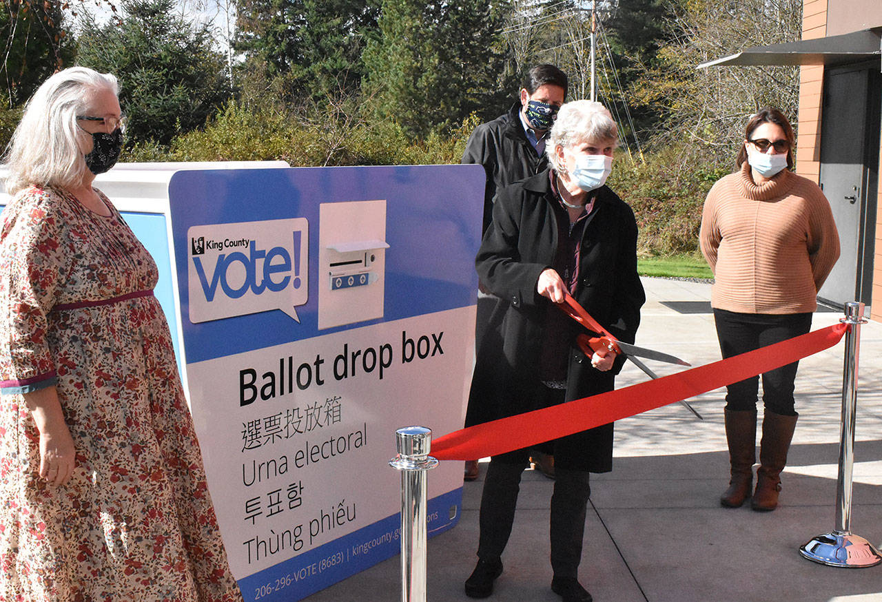 With members of the City Council looking on, Black Diamond Mayor Carol Benson cuts a ceremonial ribbon, opening a ballot drop box at the library. Photo by Kevin Hanson