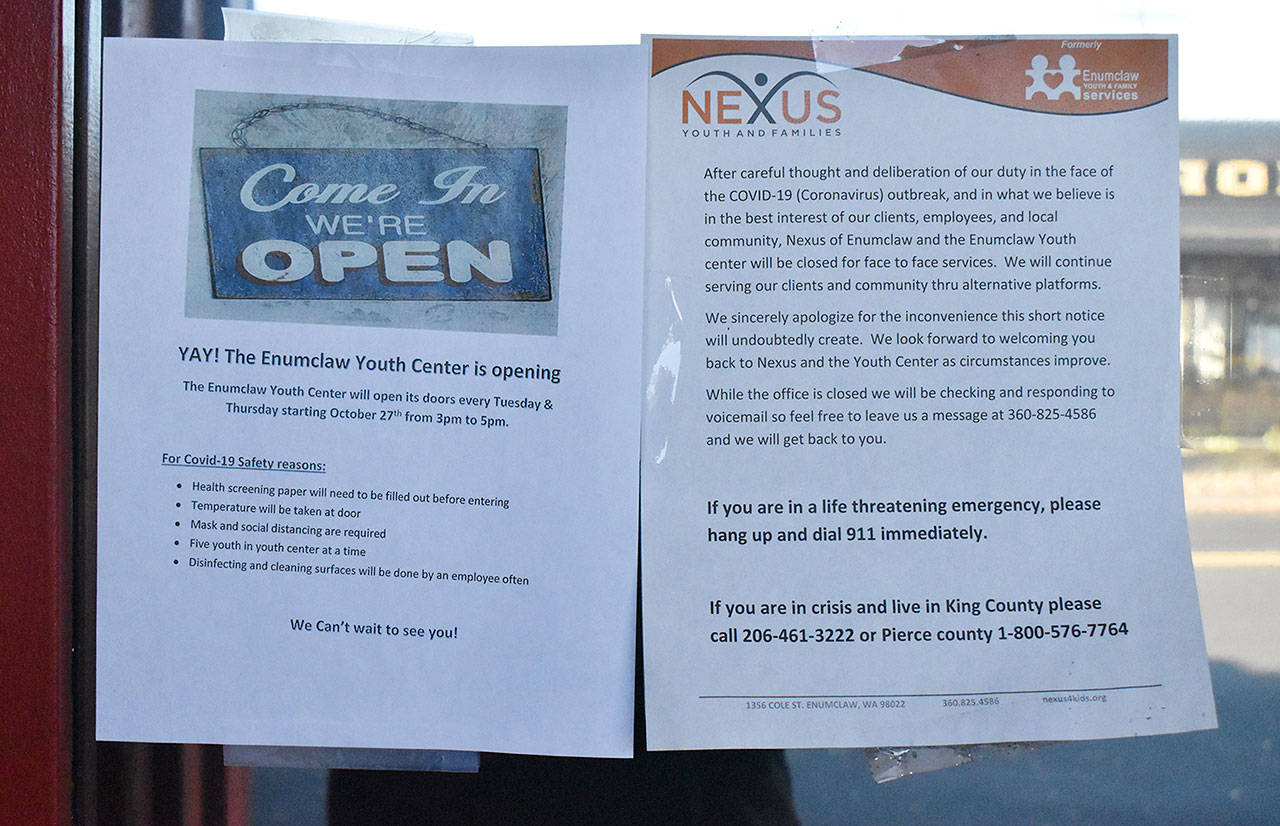 Two signs are found on the Enumclaw Youth Center window this week. The older, on the right, explains the center’s March closure. The sheet on the left announces the center will now be open four hours per week. Photo by Kevin Hanson