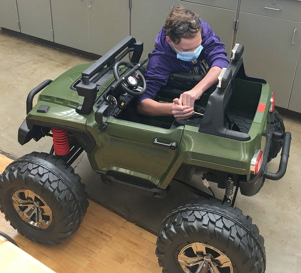 Enumclaw’s Eli Murphy spent an estimated 75 hours modifying an electric car for a Colorado boy with special needs (pictured here). The local photos show Eli modifying the vehicle’s seatbelt and putting finishing touches on a personalized license plate.