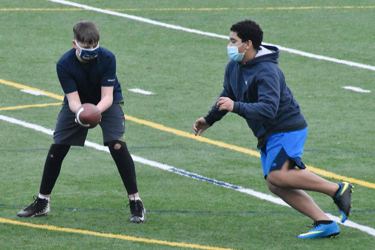 White River football players were running through drills last week, with masks in place and players spread throughout the practice field. Here, coach Jesse Reeves leads the way while Jayden Sams hands off to Ossyan Williams. Football practice for real is set to begin Feb. 10. Photo by Kevin Hanson