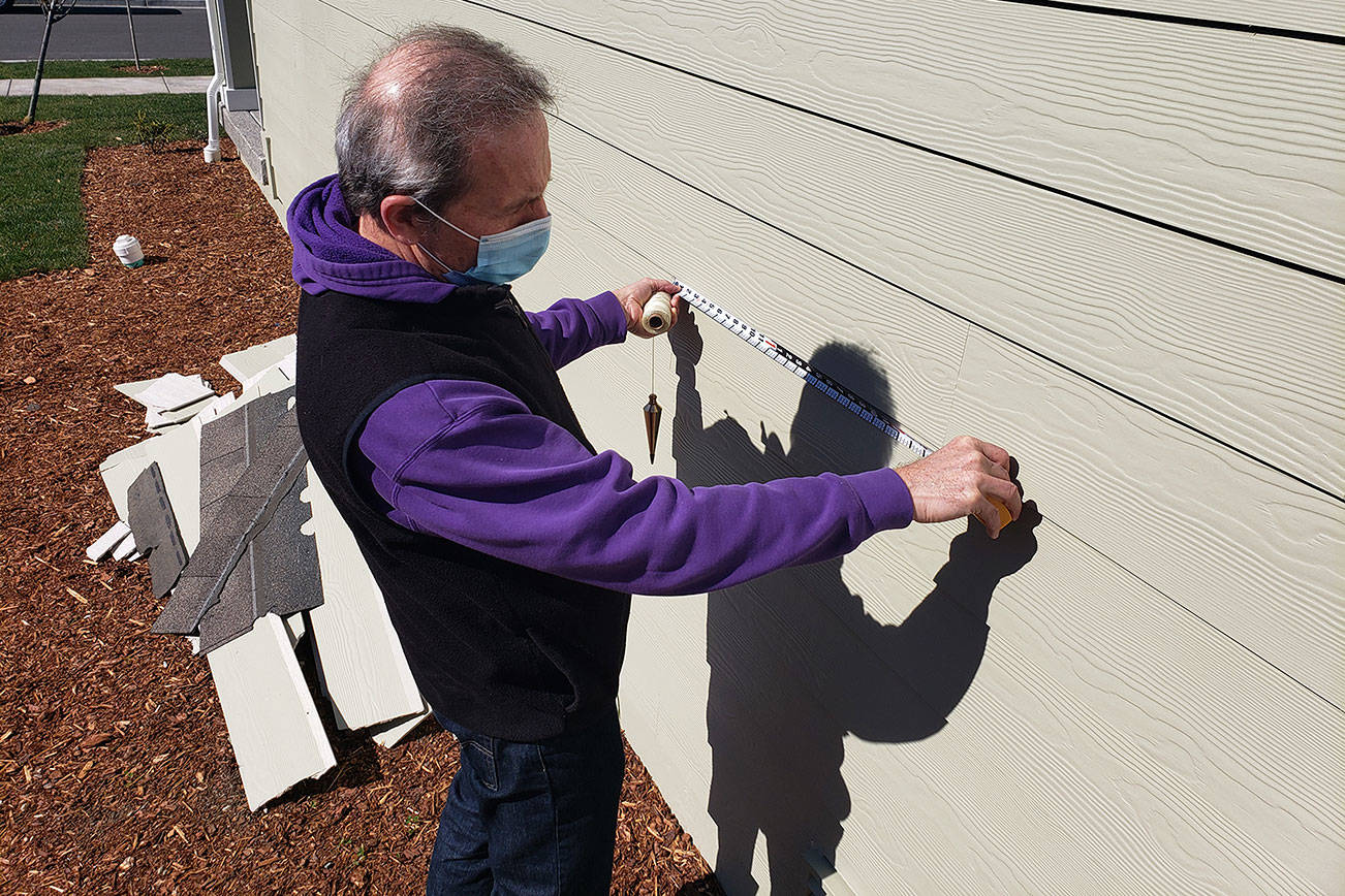 Construction expert Will Martin taking some measurement of the siding of a house in Enumclaw's Suntop Farms. Photo by Ray Miller-Still