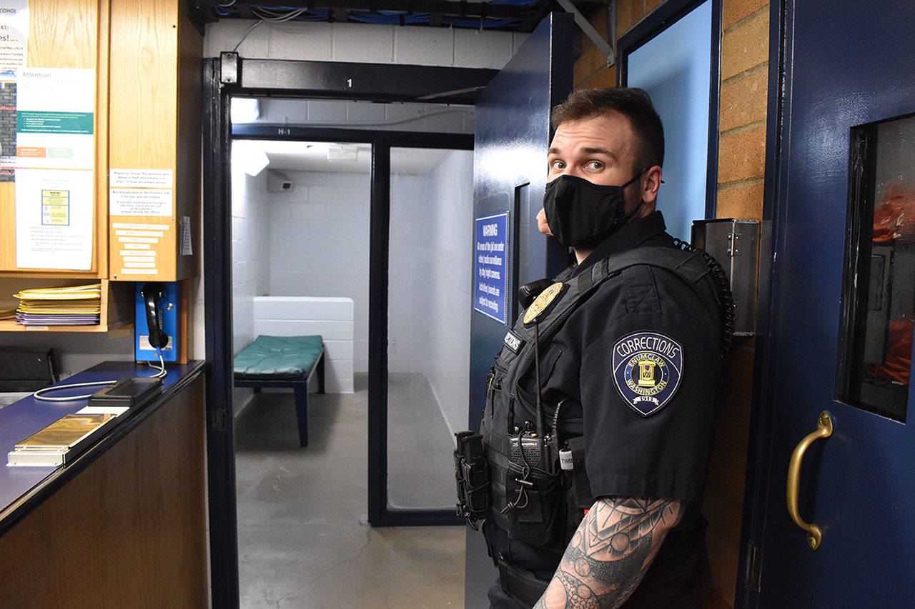 Enumclaw Police Correctional Officer Tyler Ewalt holds open the door to a holding cell at the police department’s jail the afternoon of April 5. The cell, while not the one he rushed to when an inmate attempted suicide last month, is nonetheless where inmates in crisis are typically held. Photo by Alex Bruell